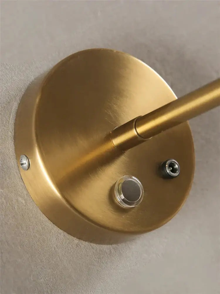 Modern gold finished wall sconces with decorbites glass lampshade featuring a circular base and slender rod for bedroom decor
