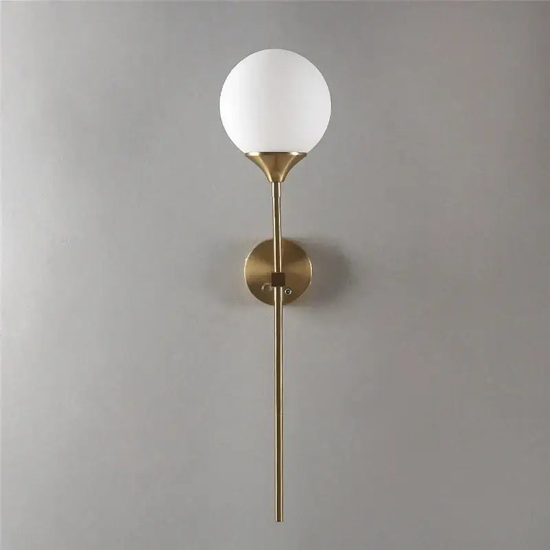 A sleek brass wall sconce with a frosted white spherical decorbites glass lampshade wall for bedroom light
