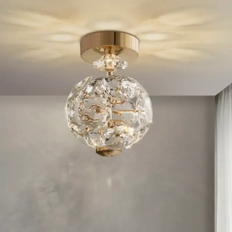 Modern gold spherical crystal pendant chandelier with intricate cut glass facets emitting warm light for bedroom