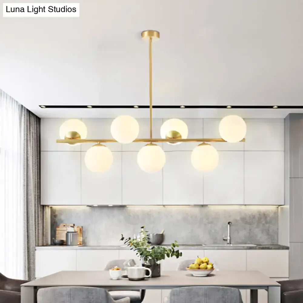 Modern gold brass-finished island ceiling light with six frosted glass globes in a horizontal pendant lighting design