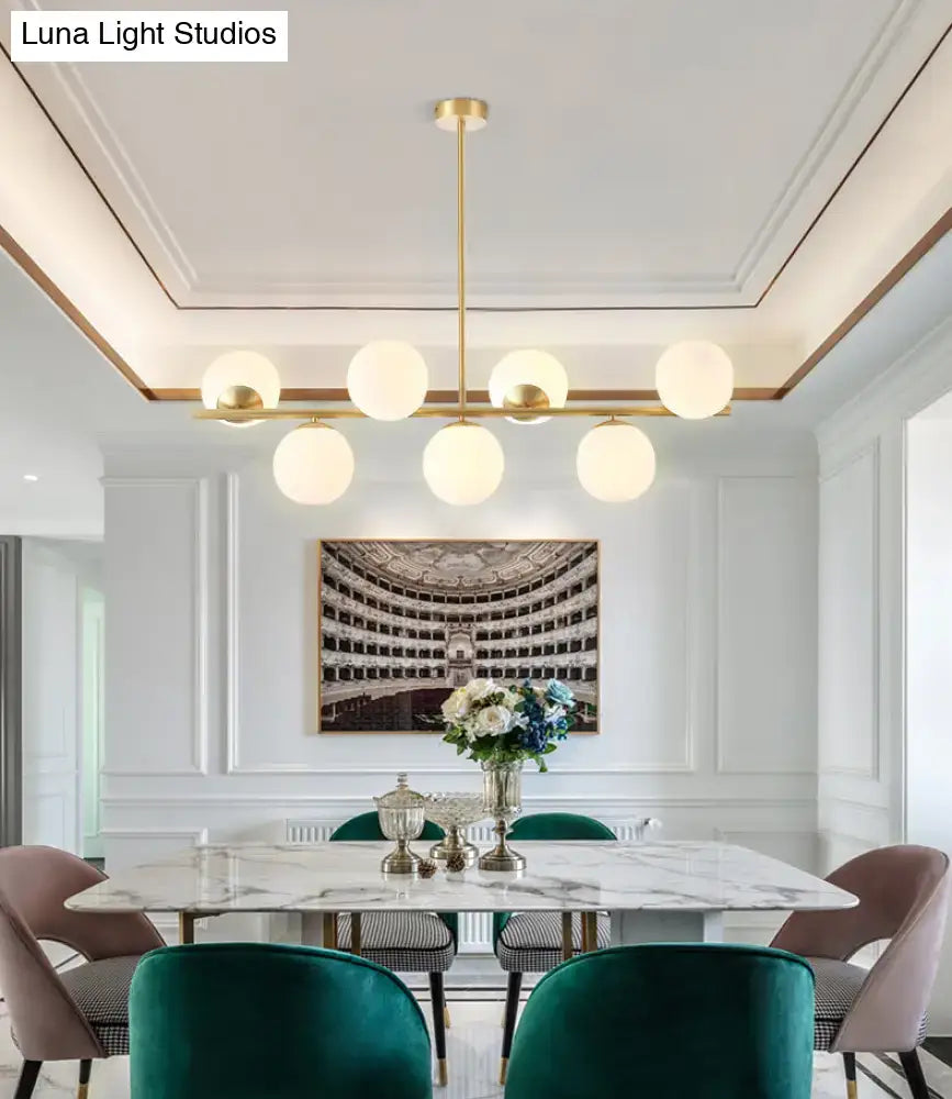 Modern gold-toned island ceiling light with six frosted glass globes pendant lighting for dining rooms