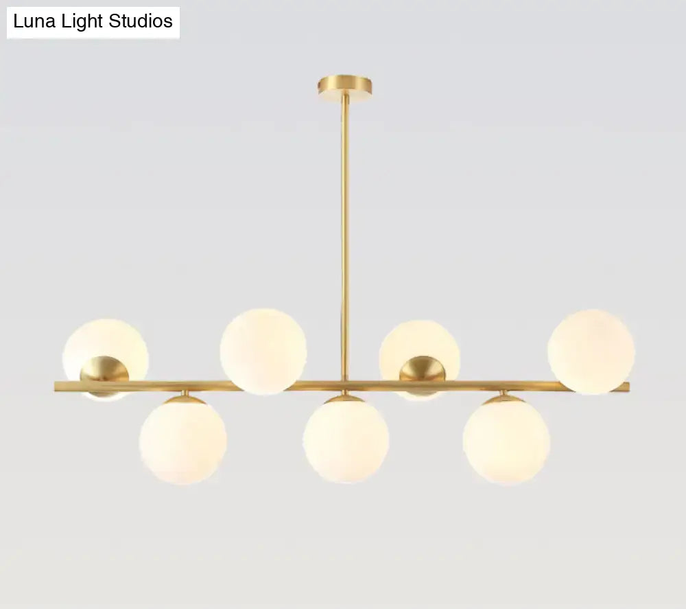 Modern gold spherical island ceiling light with six frosted glass globes in a linear pendant lighting design