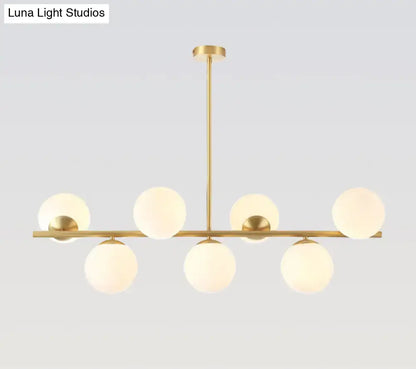 Modern gold spherical island ceiling light with six frosted glass globes in a linear pendant lighting design