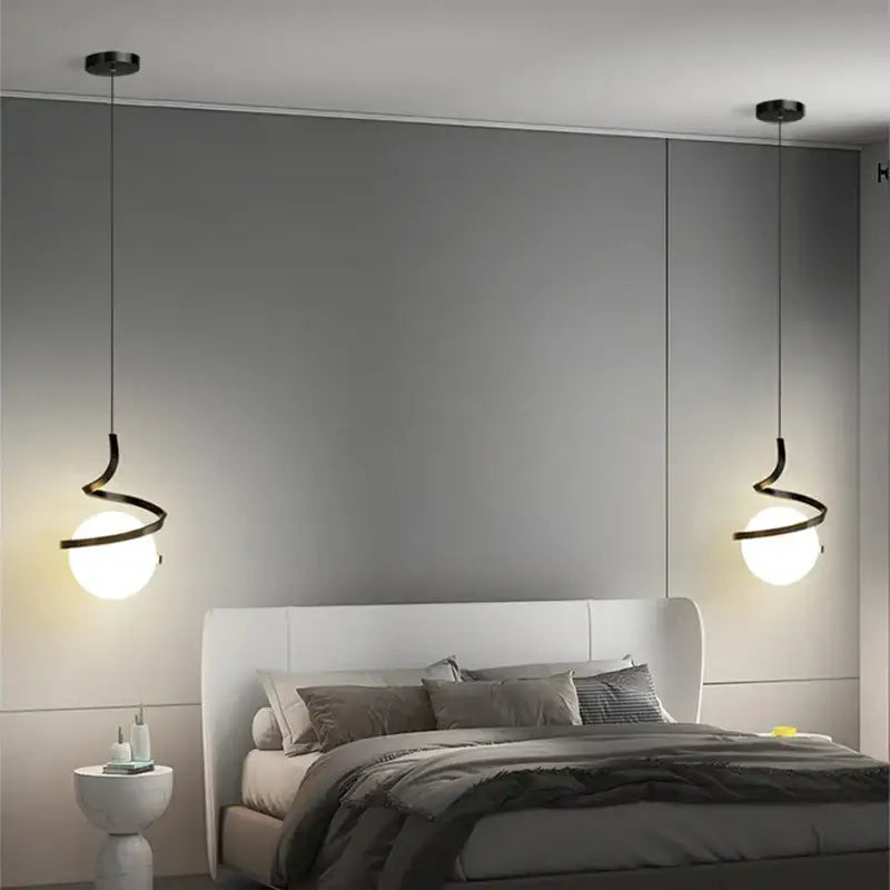 Modern black spiral pendant light with frosted glass globes and iron finish hanging symmetrically above bed