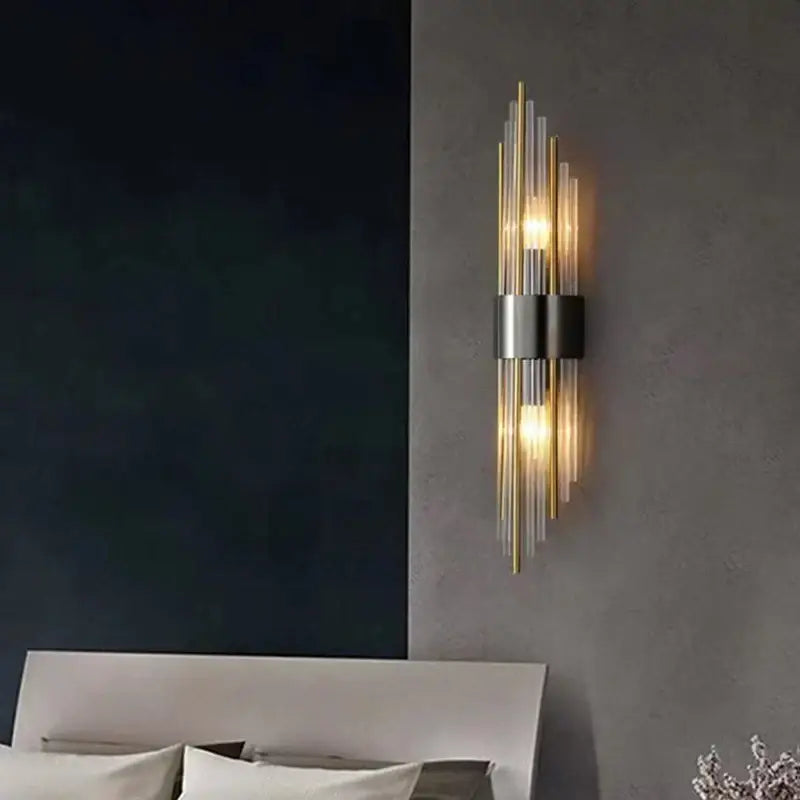 Modern gold stainless steel wall lamp with clear crystal rods and brushed metal band emitting warm light for bedroom sconce