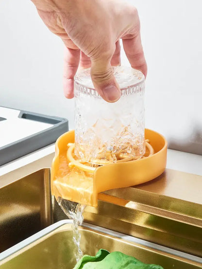 Yellow plastic sink drain catcher with clear glass on modern gold stainless steel waterfall kitchen sink set
