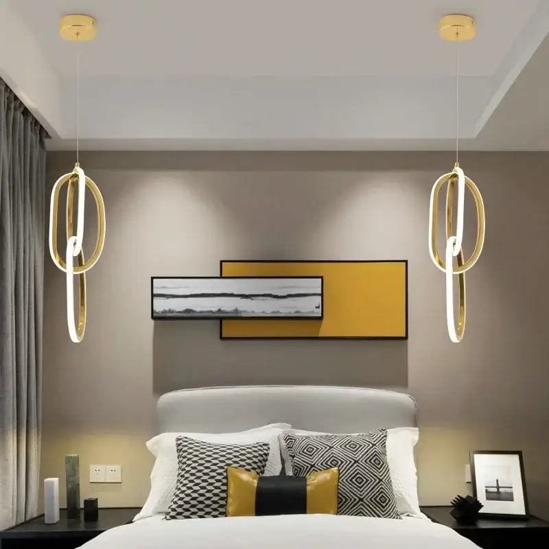Modern gold steel pendant light with interlocking rings and integrated led lighting hangs symmetrically above bed decorbites gold steel pendant