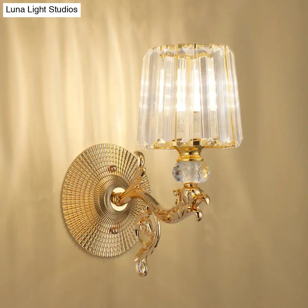 Modern gold tapered wall light fixture with ornate scrollwork and faceted crystal shade for bedroom sconce use