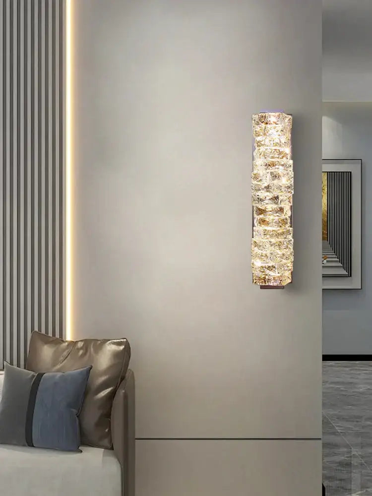 Modern gold textured glass wall sconce lamps with stacked crystal segments emitting warm light for bedroom decor