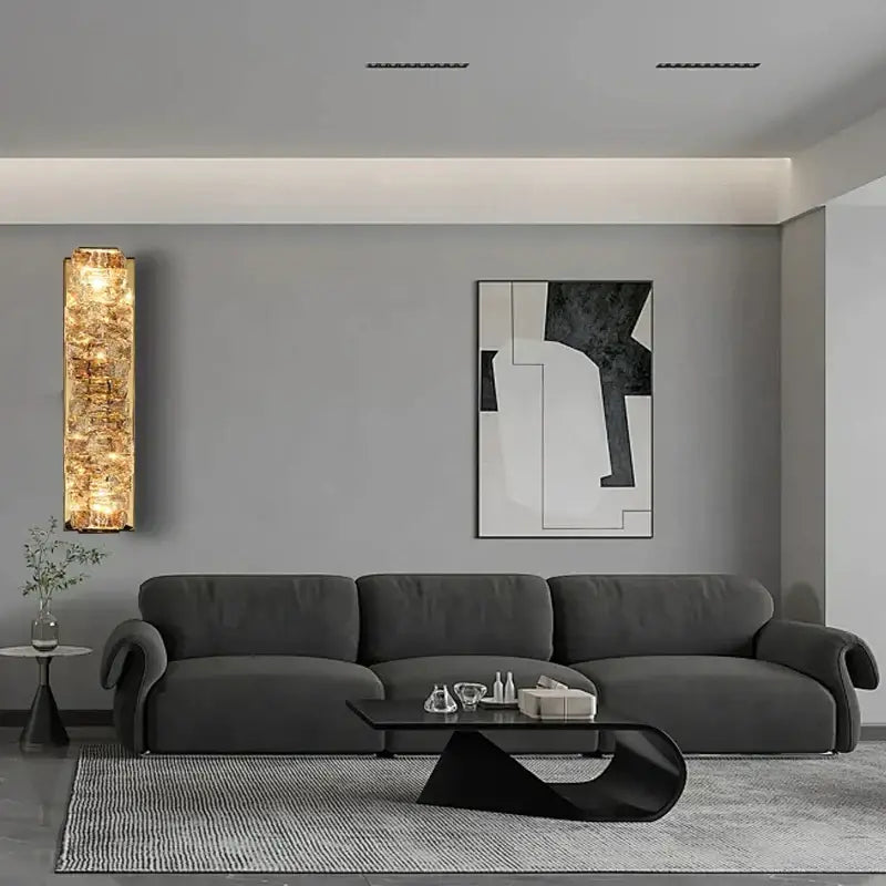 Dark gray velvet sofa with curved armrests paired with modern gold textured glass wall sconce lamps for bedroom decor