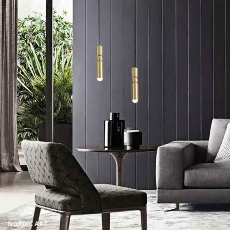 Two slender gold tube pendant lights with cylindrical shapes hang as modern kitchen bedside decorbites pendant light