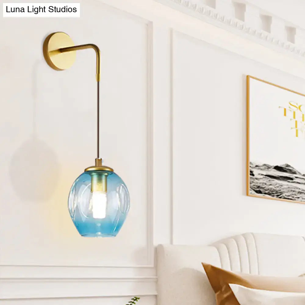 A sleek modern gold tulip wall lamp with curved brass arm and blue glass shade ideal for bedroom use