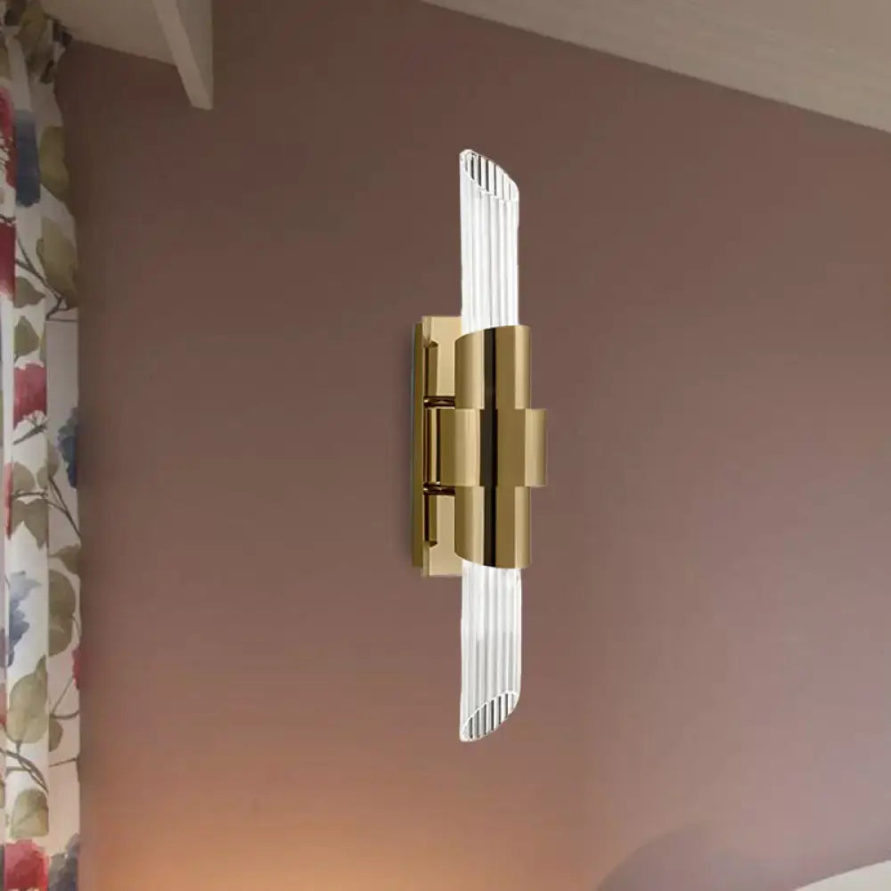 Modern gold wall lamp with prismatic crystal shade featuring vertical glass prisms and polished metal accents for bedroom