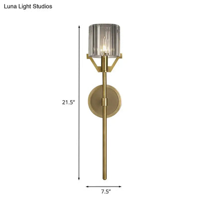 Modern gold wall light with a 21.5-inch tall brushed brass finish and clear crystal block cylinder shade for bedroom