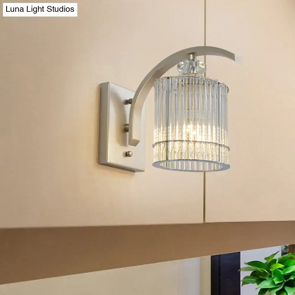 Modern silver-toned wall mounted lamp with curved arm and clear crystal shade for bedroom sconce lighting