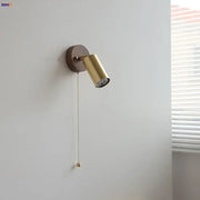 Modern gold walnut wall sconce with gold-finished circular base and pull chain switch for bedroom lighting