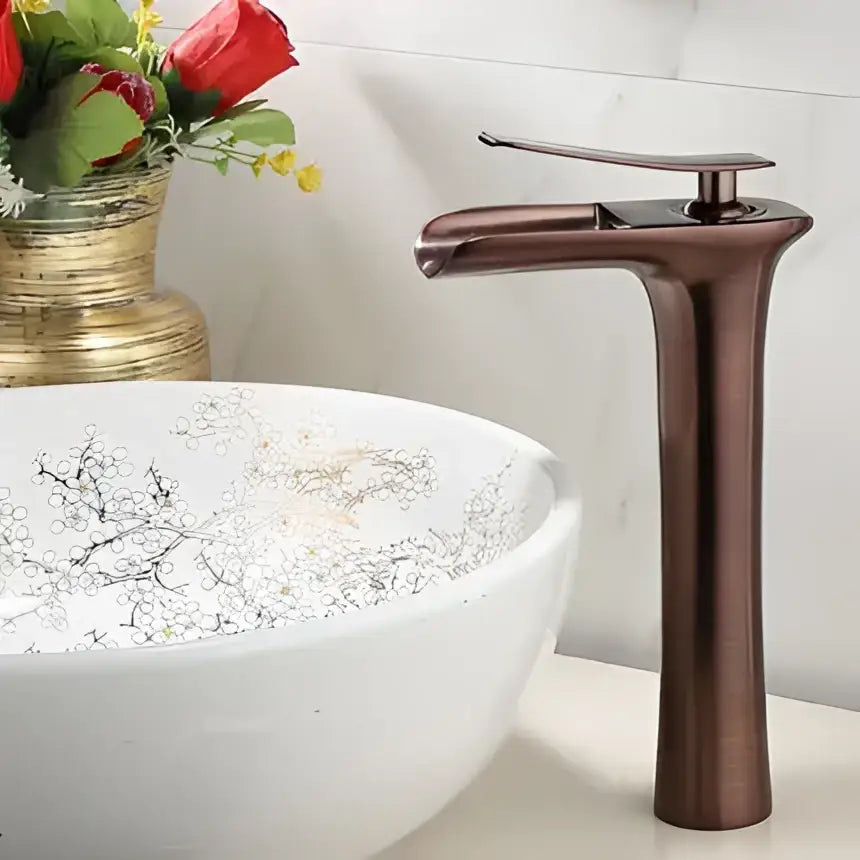 Bronze-finished decorbites gold waterfall basin faucet with sleek tall design and single lever for modern bathroom use