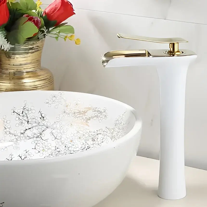 Modern gold waterfall basin faucet with sleek gold-toned finish paired with white ceramic sink with silver floral pattern decorbites gold