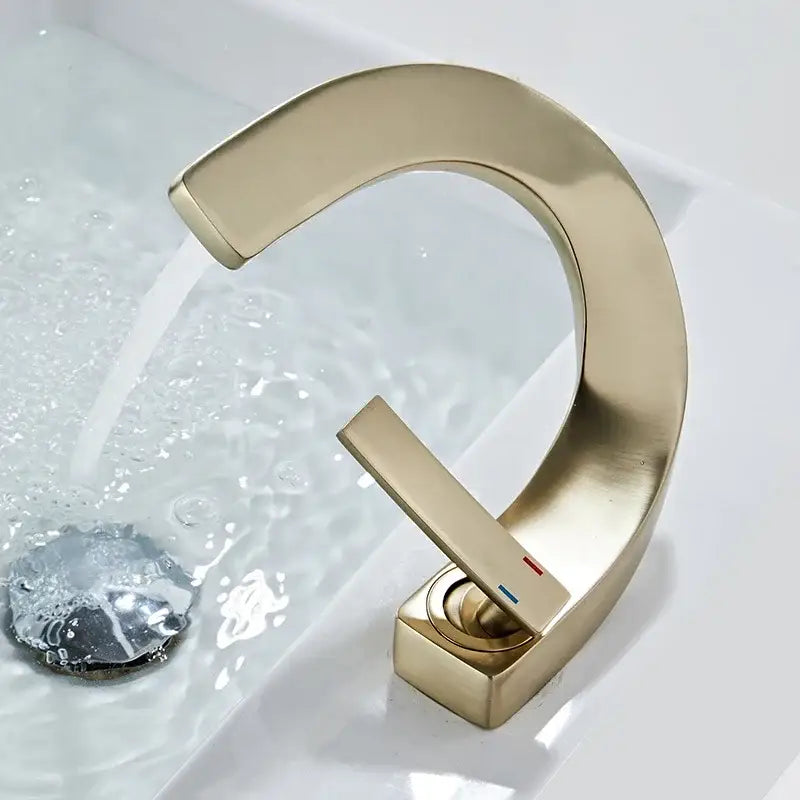Modern gold-toned decorbites brass basin faucet with sleek curved waterfall design and rectangular handle for bathroom sink