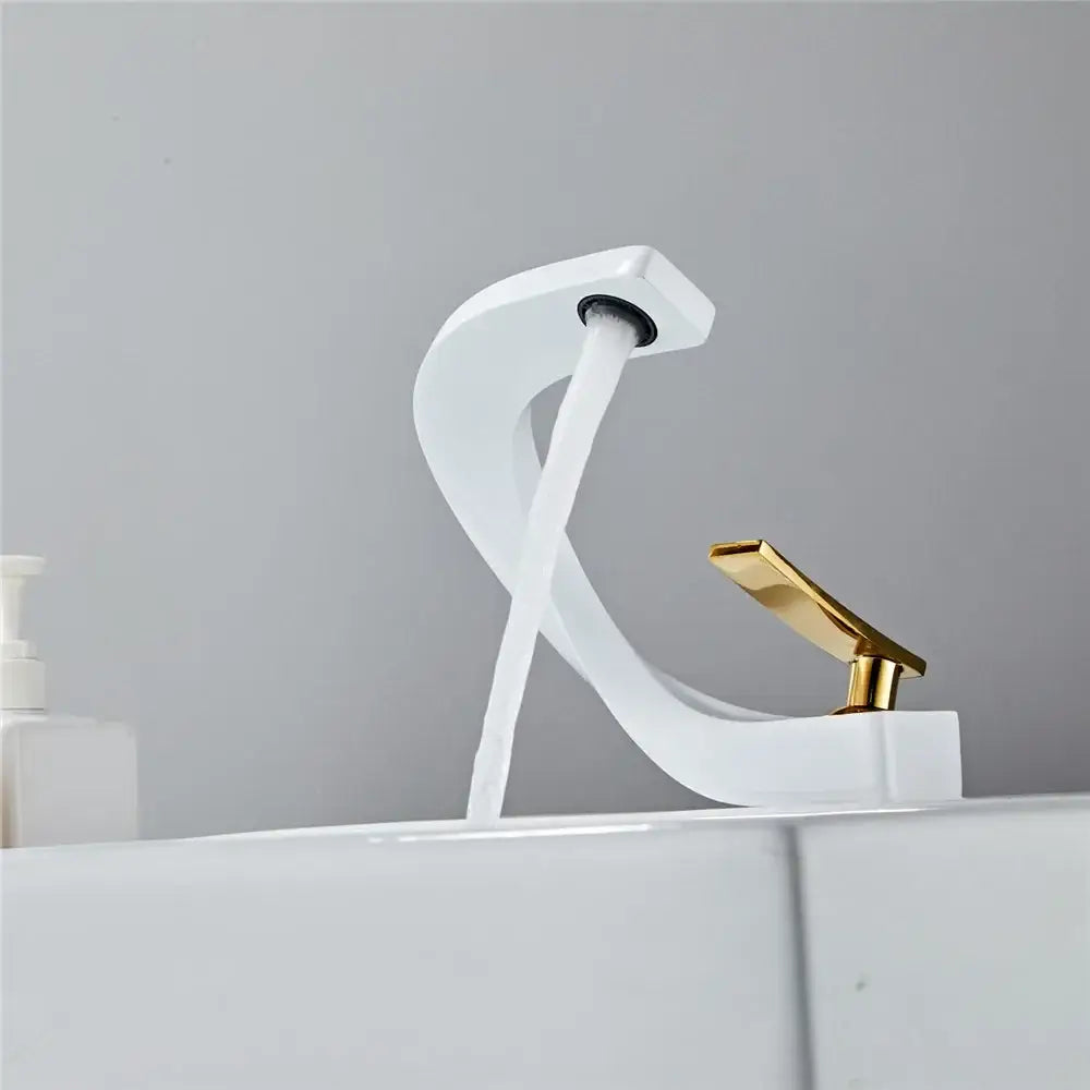 A modern gold waterfall mixer bathroom faucet with a sleek white ceramic body and elegant curved gold-tone handle