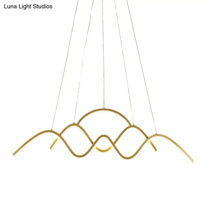 Gold-toned metal led pendant light fixture with modern wave design suspended by thin cables for dining room use