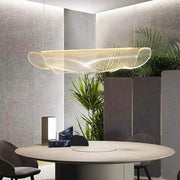 A modern gold wave mesh pendant light made of transparent material hanging above a dining room table decorbites dining room