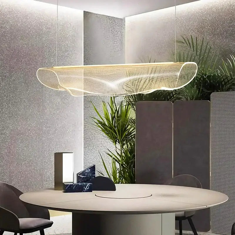 A modern gold wave mesh pendant light made of transparent material hanging above a dining room table decorbites dining room