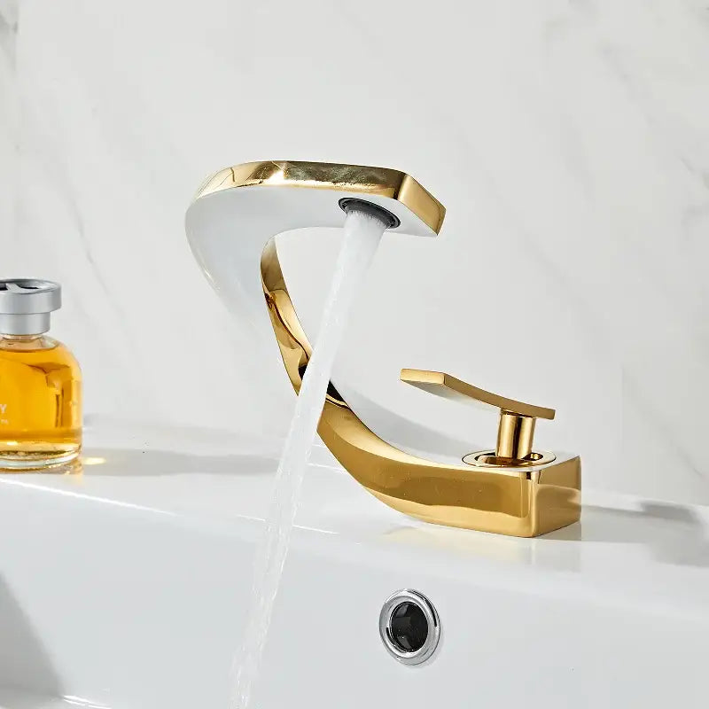 Modern gold and white bathroom basin faucet with curved gold-toned waterfall spout and polished metallic finish for decorbites gold white bathroom decor