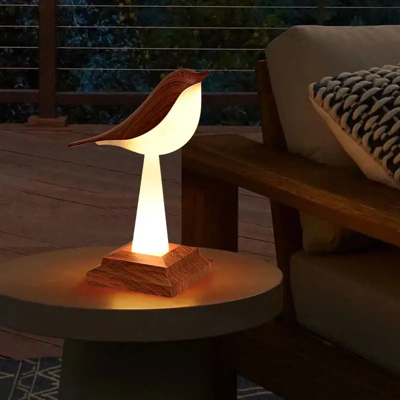Warmly glowing gold and white decorbites bird table lamp with wooden body and smooth illuminated interior for desktop use