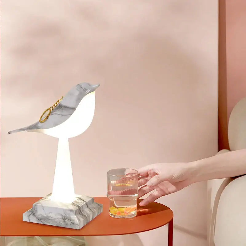 Modern gold and white bird table lamp with white illuminated body and gray marble wings for desk decorbites bird table