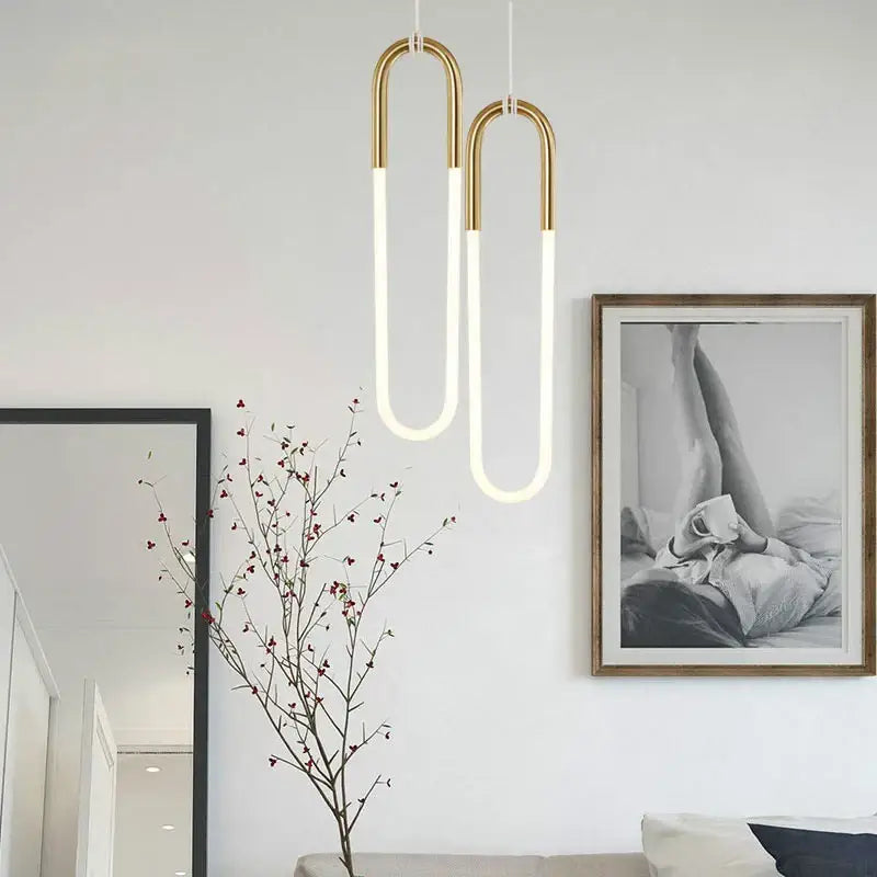 Two modern gold pendant lights with white LED tubes and metal frames hang in living room decorbites gold pendant style