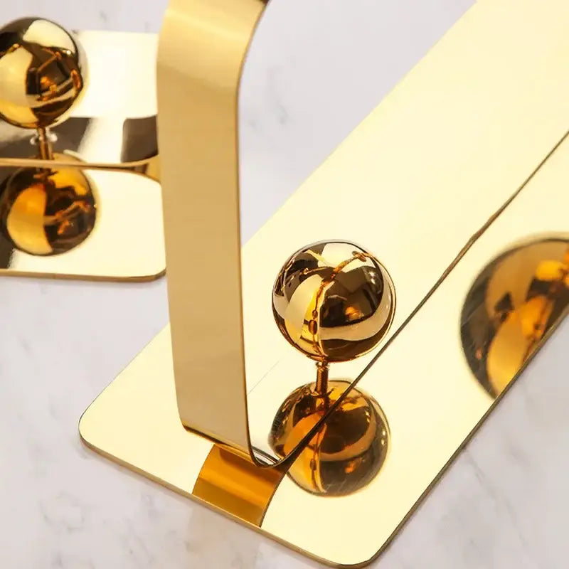 Gold-colored metallic bookend with sleek curved design and polished spherical accents for living room decorbites golden ball decor