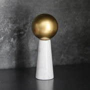 A modern golden ball spherical ornament on a white marble cone pedestal for stylish living room decor