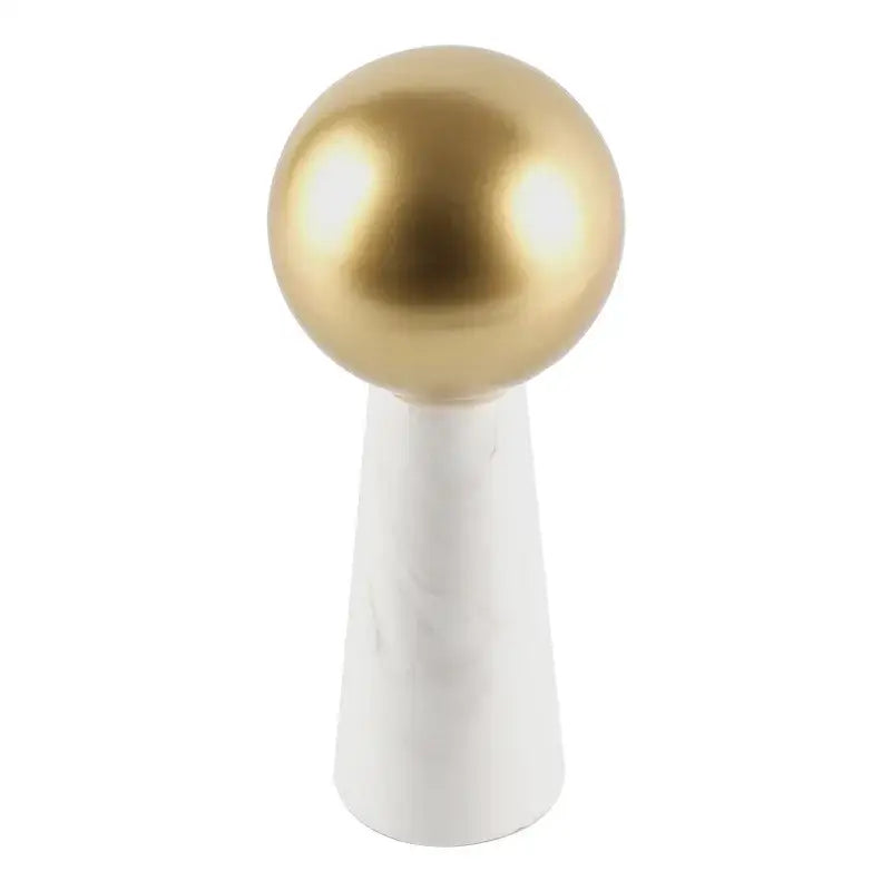 A modern table lamp with a golden ball shade and white marble cone base as a living room spherical ornament