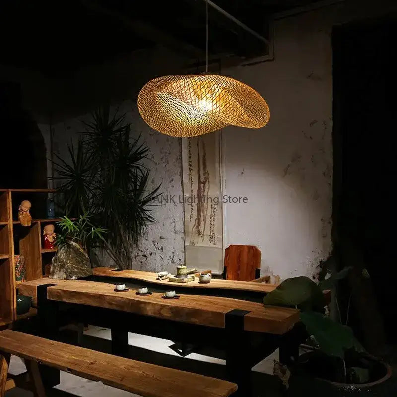 A warm golden-brown woven bamboo wave shade pendant lamp hangs above a rustic wooden dining room table