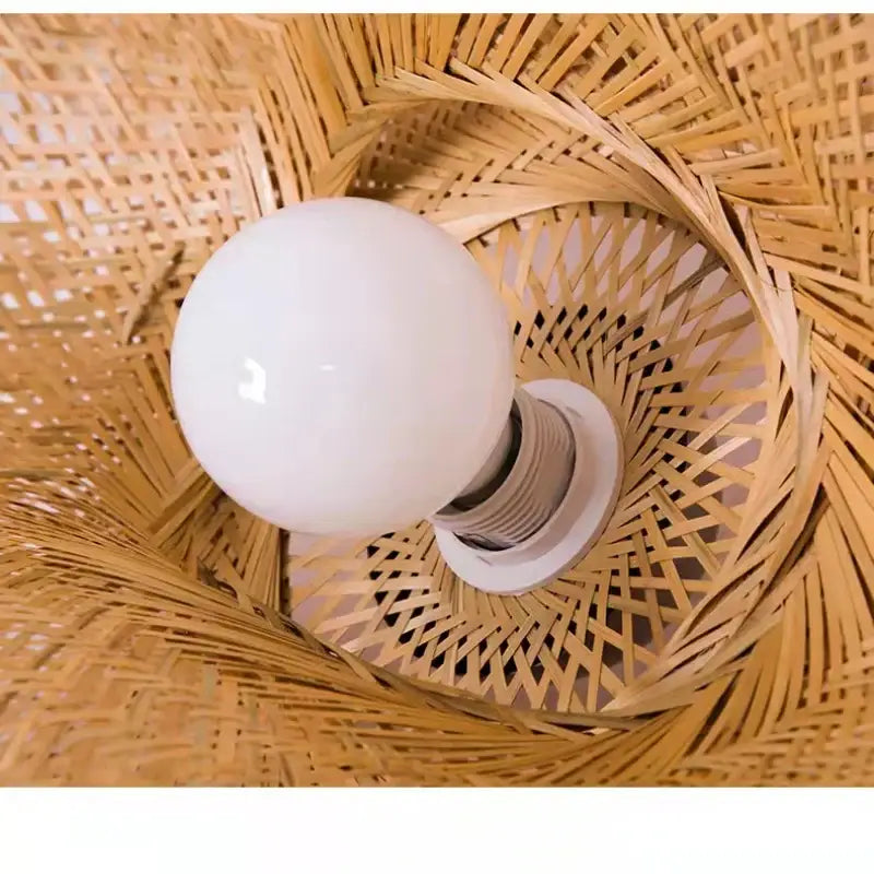 Modern golden bamboo woven chandelier tea room pendant light with a white spherical bulb inside a woven bamboo shade