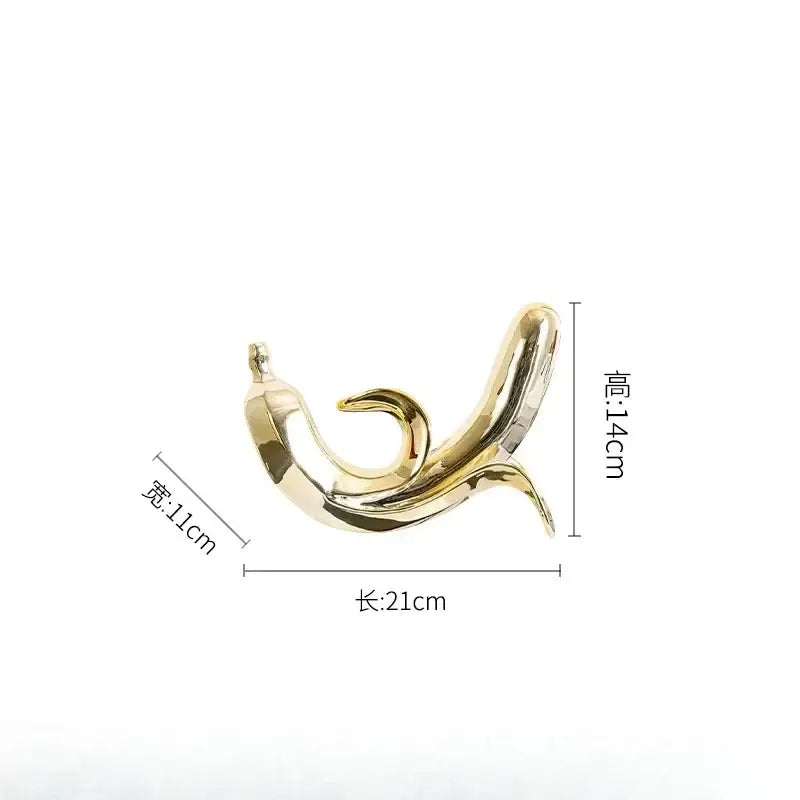 A sleek golden banana figurine made of metallic material with a smooth reflective surface for living room decor