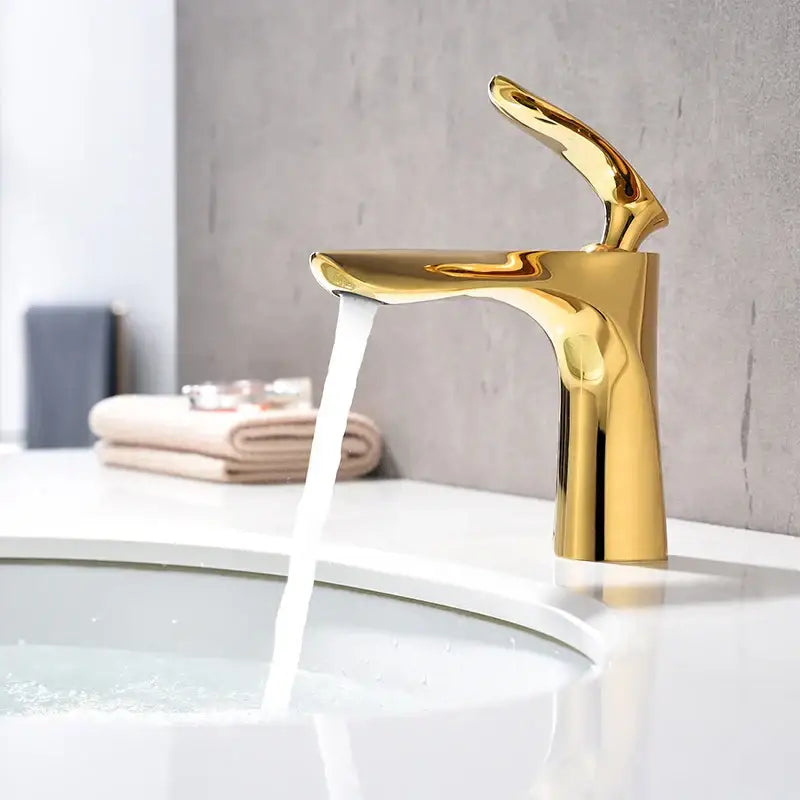 A sleek modern decorbites golden bathroom faucet with a polished metallic finish and curved single handle basin tapware