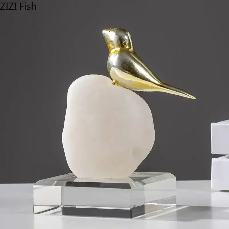 A sleek golden bird statue perched on a smooth milky-white stone base for modern living room decor
