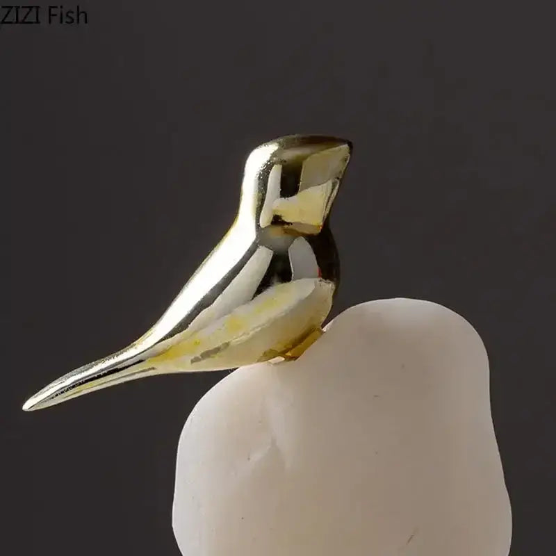 Modern golden bird statue with sleek gold-toned metallic finish and subtle yellow accents on stone base for living room
