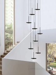 Modern golden black led long black circular pendant chandelier by decorbites hangs above staircase decor