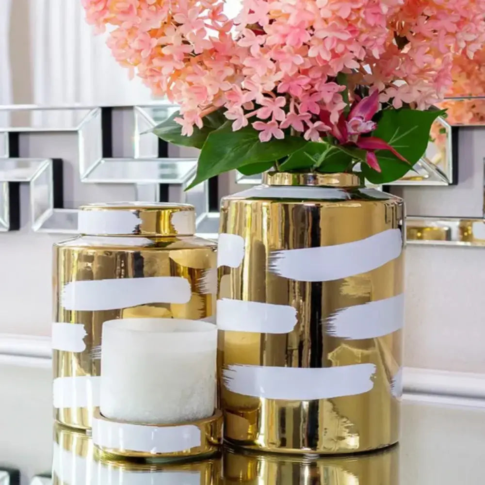 Modern decorbites golden ceramic vase with white brushstroke stripes and lid holding pink hydrangeas for living room storage
