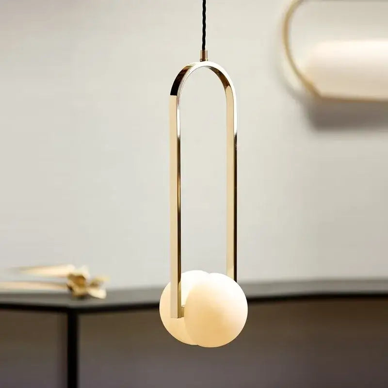 Modern pendant lights with a sleek gold-toned metal frame and off-white glass spheres by decorbites golden chandelier