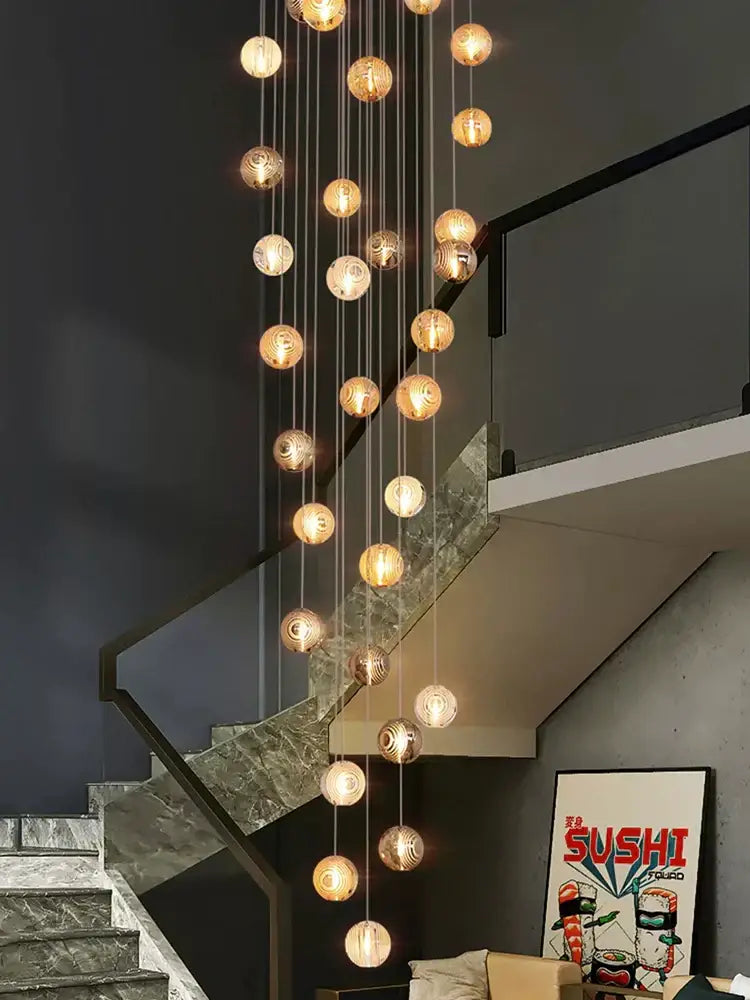 Modern golden crystal glass spiral ceiling chandelier with warm glowing spherical orbs above staircase decorbites crystal glass