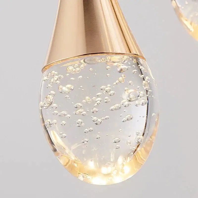 A teardrop crystal led staircase chandelier with brushed gold metal top and bubble-filled glass for lobby decorbites lighting