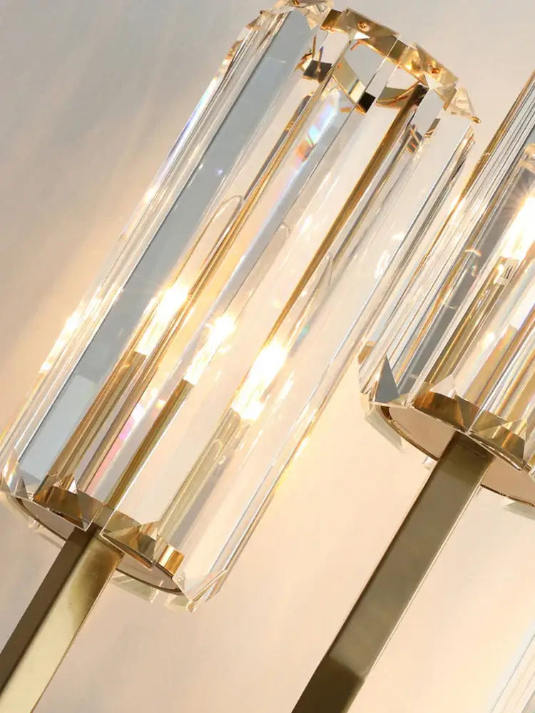 A modern golden decorbites crystal wall light with faceted crystal cylinders in polished gold finish for bedroom