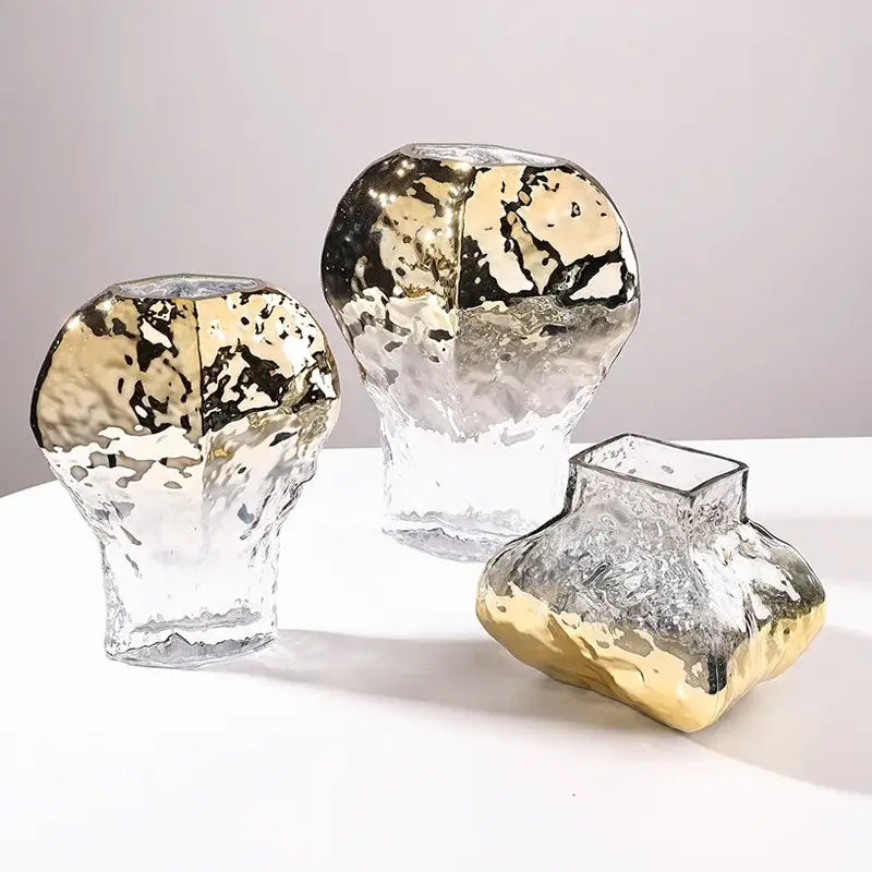 Three modern golden geometric glass vases with textured hammered finish and gold leaf accents for living room decor
