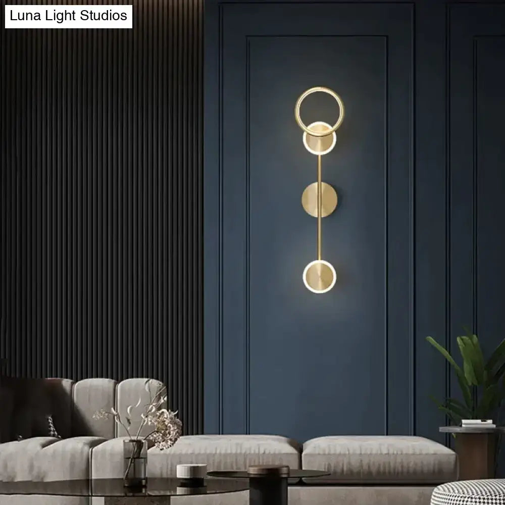 Gold-toned modern led wall lamp with three stacked circular rings and vertical rod for living room lighting