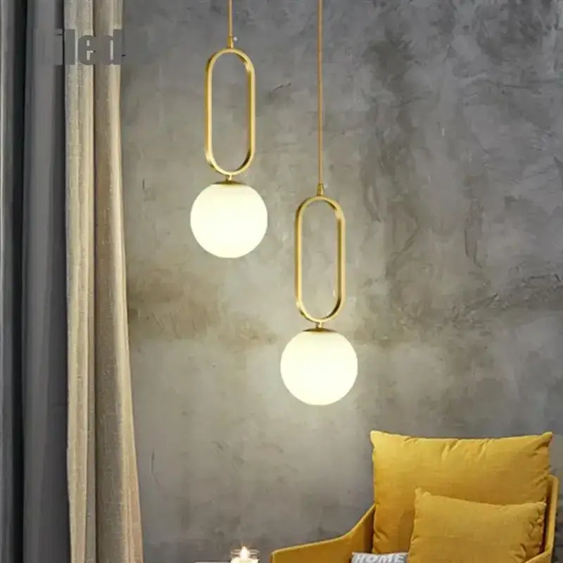 Modern golden glass ball pendant light with gold-toned oval metal frame and frosted glass globe shades from decorbites