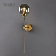 Modern golden glass ball wall lamp with a gold-toned stem and spherical smoked glass globe decorbites golden glass sconce